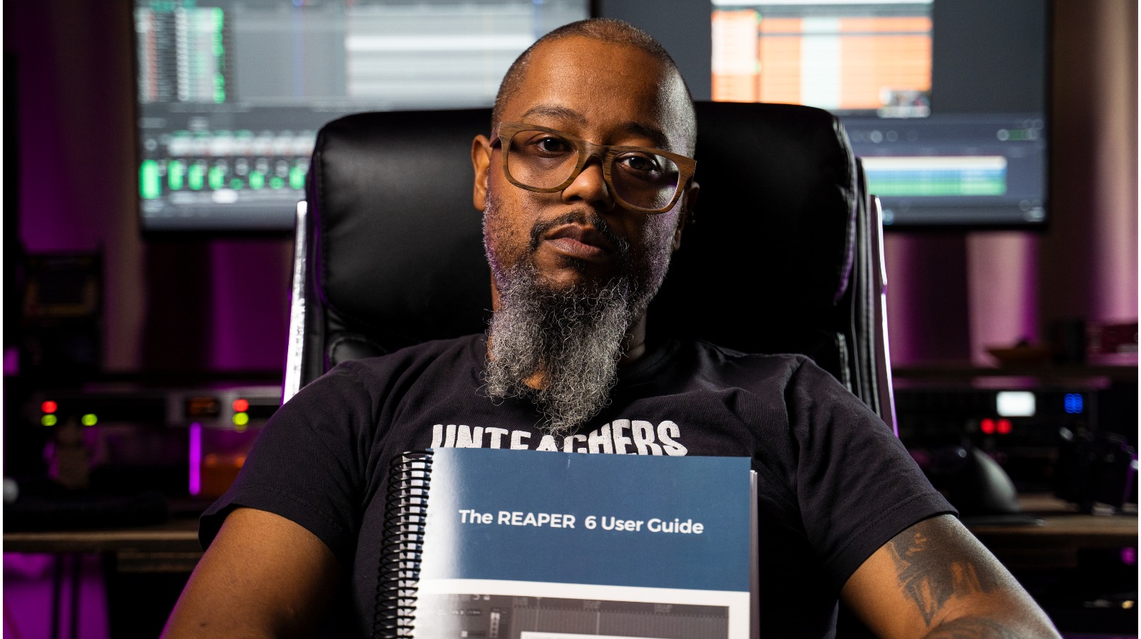 myk robinson sitting in a chair holding a reaper user guide book